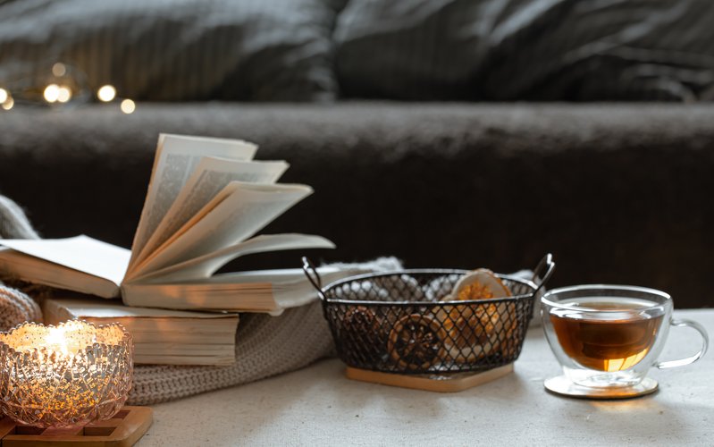 A minimalist stack of books on a wooden surface with soft warm light, suggesting quiet reflection and slow reading
