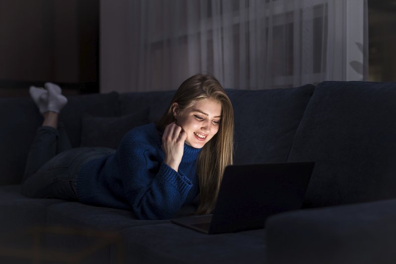 A person working late at night in a dark room, illuminated only by the screen, representing the false energy of a second wind.